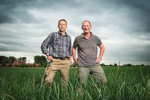 Outdoor portrait of 2 farmers in a field of onions