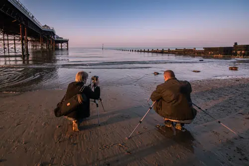 Photographers with tripods set up by Cromer pier for landscape photography training session